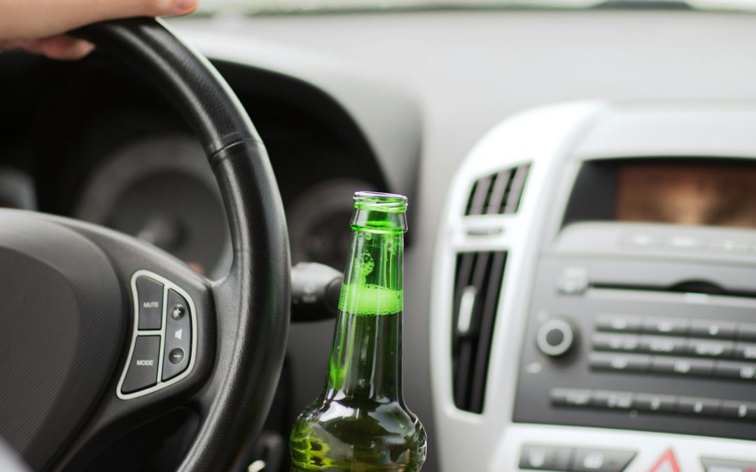 man drinking alcohol while driving the car